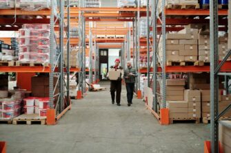 Allée d'entrepôt logistique e-commerce avec rayonnages et préparateurs de commandes
